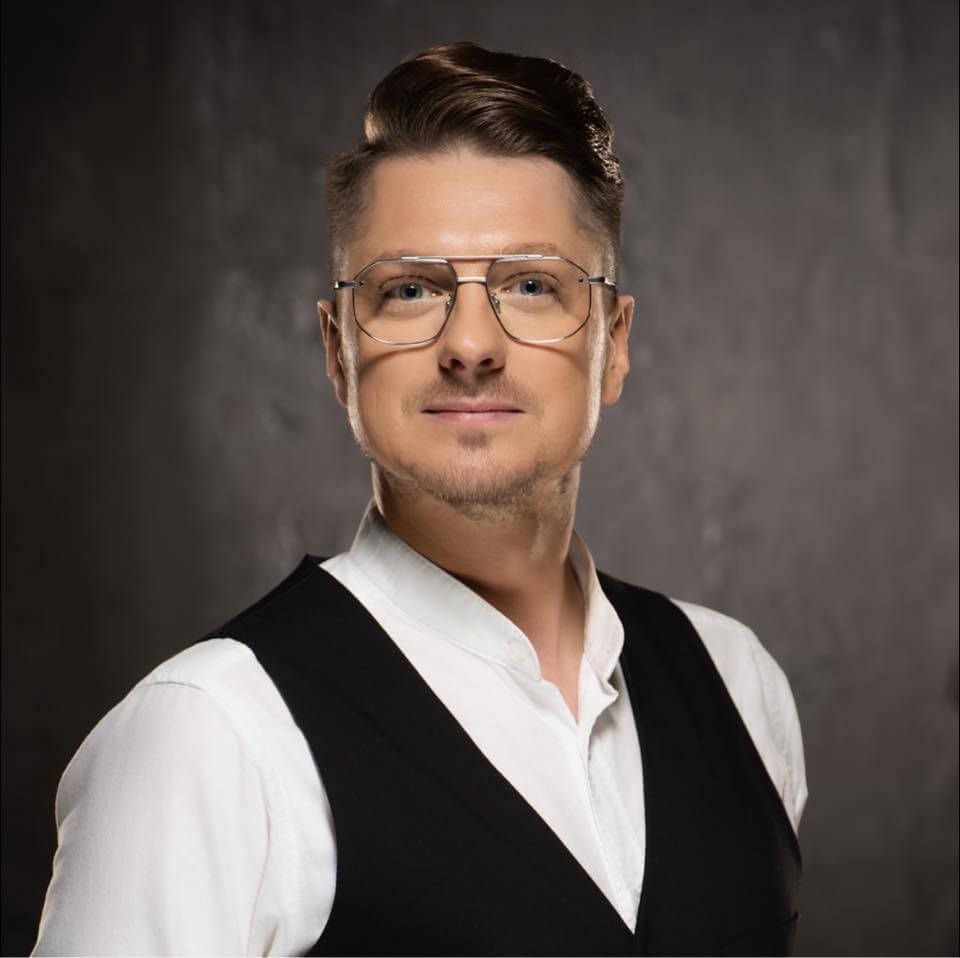 Portret mężczyzny w okularach na neutralnym tle.